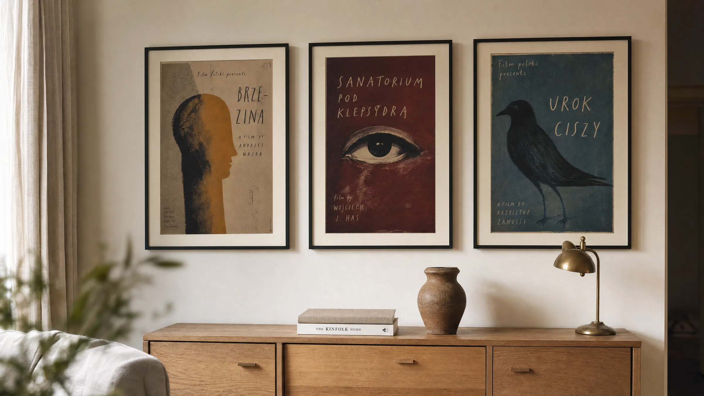 Wohnzimmerwand mit gerahmten polnischen Filmplakaten in gebrochenen Farbtönen über einem hölzernen Sideboard